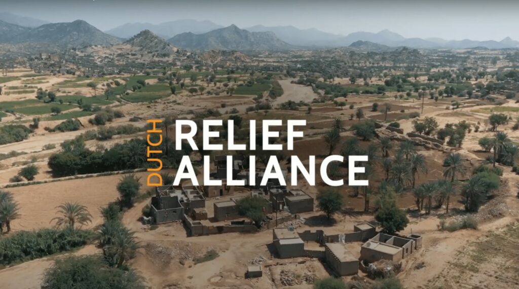 DRA relief alliance logo over a desert landscape with scattered buildings and greenery, highlighting the organization’s efforts in providing emergency aid in crisis situations.